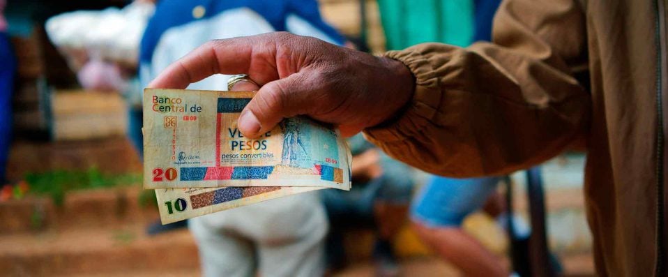 Main d'un homme tenant des billets cubains
