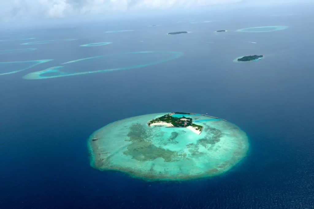 Vue aérienne d’un atoll des Maldives entouré d’eau turquoise, destination idéale pour un voyage de noces de luxe avec VeryChic