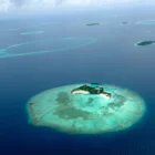 Vue aérienne d’un atoll des Maldives entouré d’eau turquoise, destination idéale pour un voyage de noces de luxe avec VeryChic