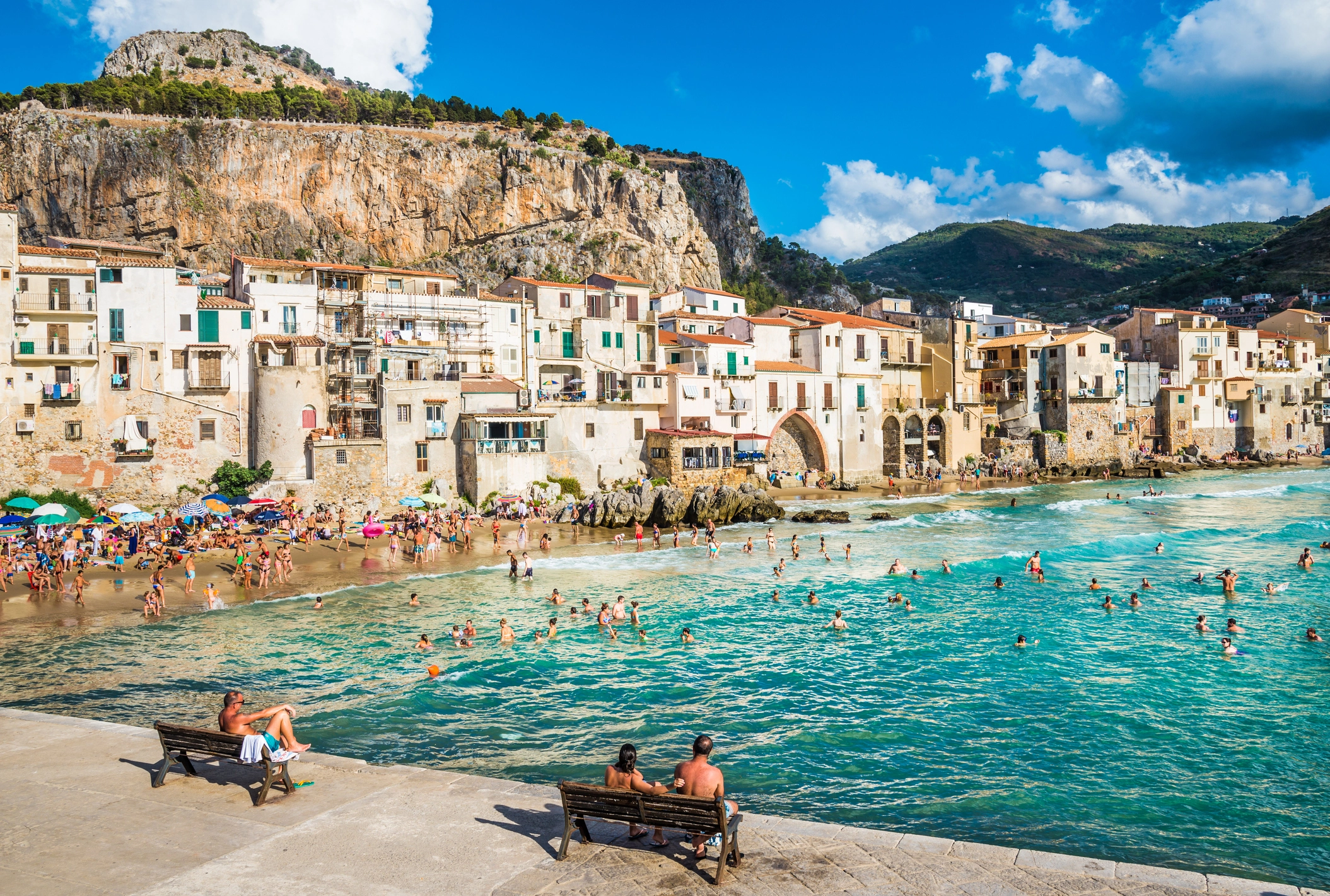 Plage de Cefalù avec vieille ville médiévale en arrière-plan, maisons colorées et mer calme