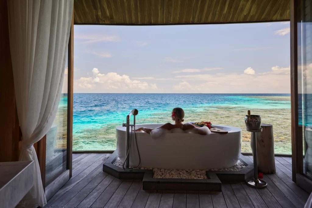 Femme se détendant dans une baignoire avec vue sur le lagon dans une villa de luxe aux Maldives