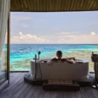 Femme se détendant dans une baignoire avec vue sur le lagon dans une villa de luxe aux Maldives