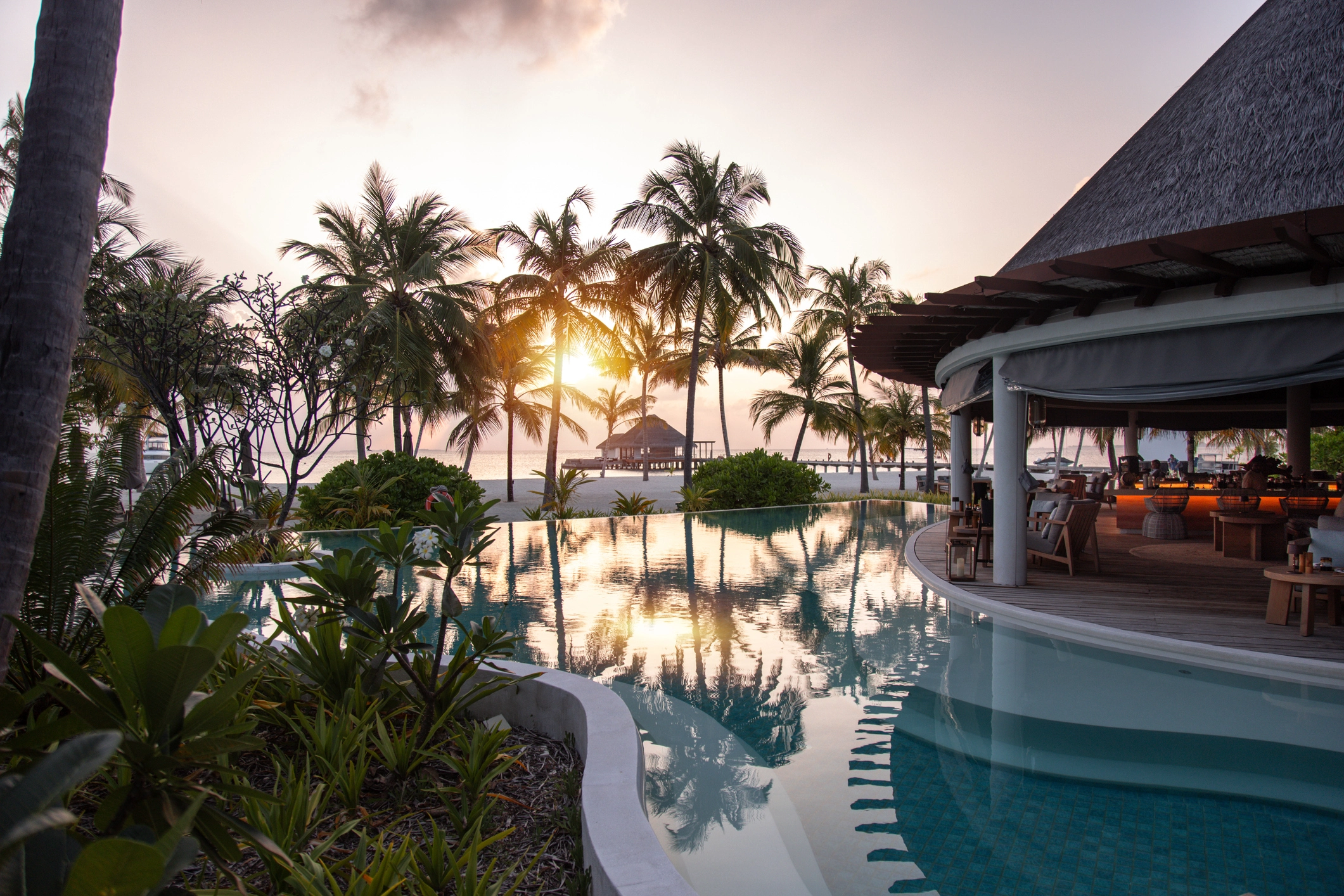 Resort de luxe aux Maldives avec piscine et palmiers au coucher du soleil