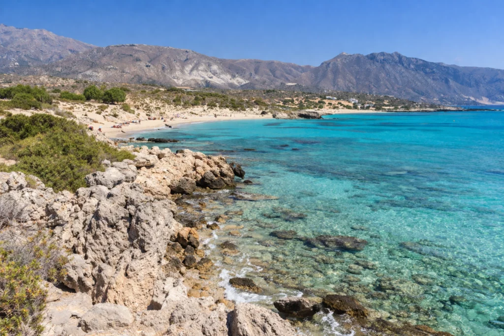Plage de Balos en Crète avec eau turquoise cristalline, rochers et montagnes en arrière-plan sous ciel bleu