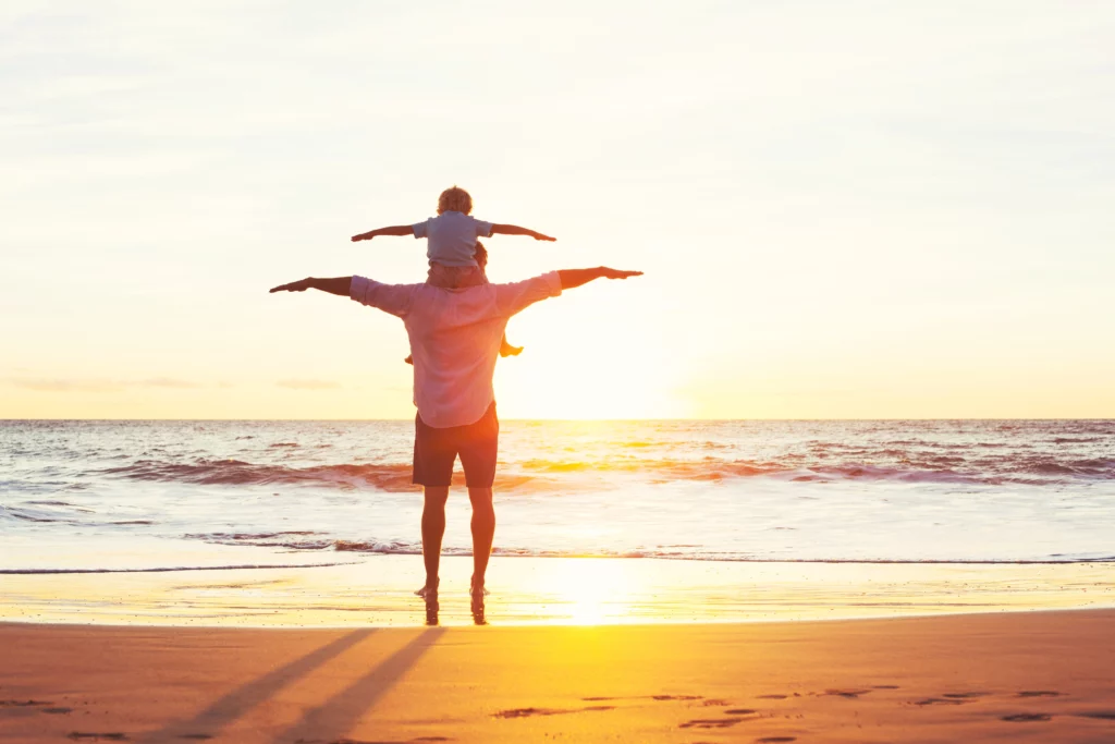 Père et fils jouant sur la plage au coucher du soleil